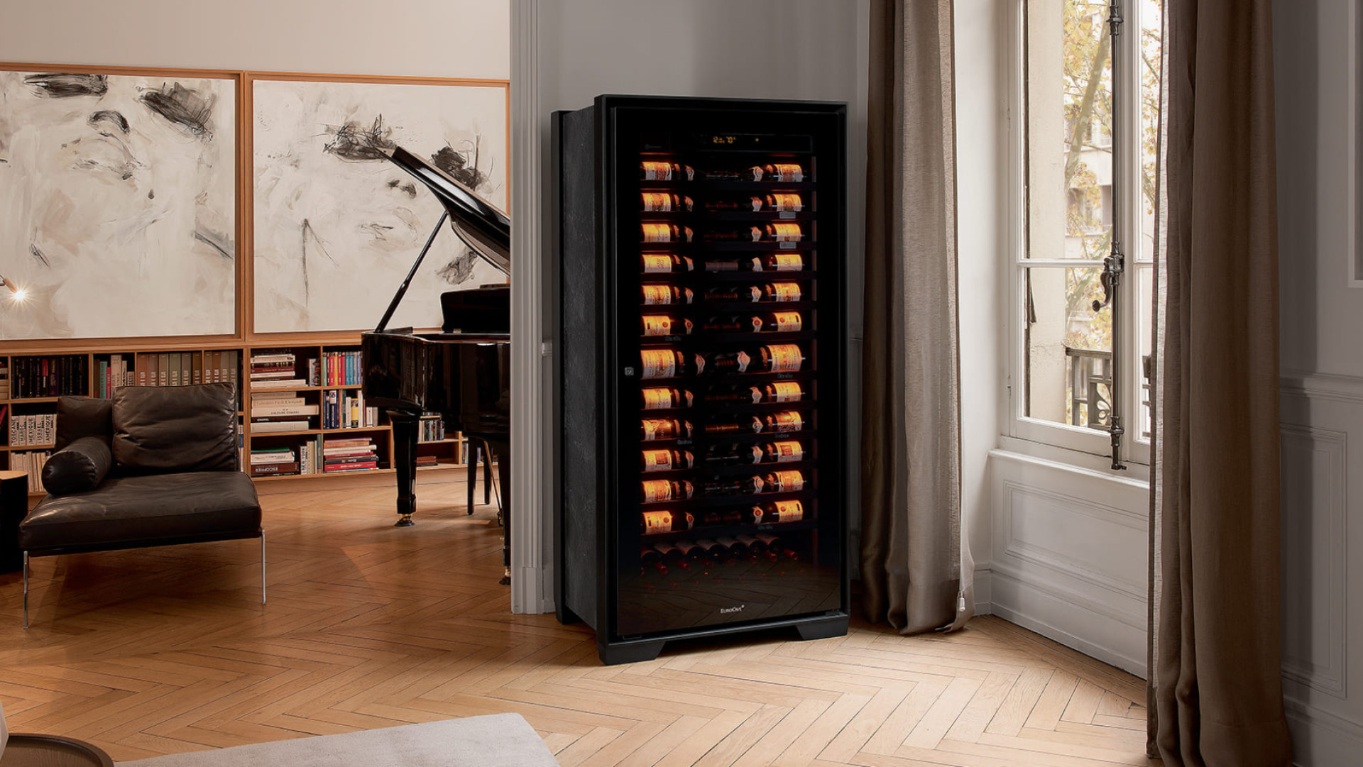 Cave à vin de vieillissement Royale installée dans le salon d’un musicien ; en arrière-plan un piano à queue et des tableaux. Cave à vin de vieillissement Royale installée dans le salon d’un musicien ; en arrière-plan un piano à queue et des tableaux.