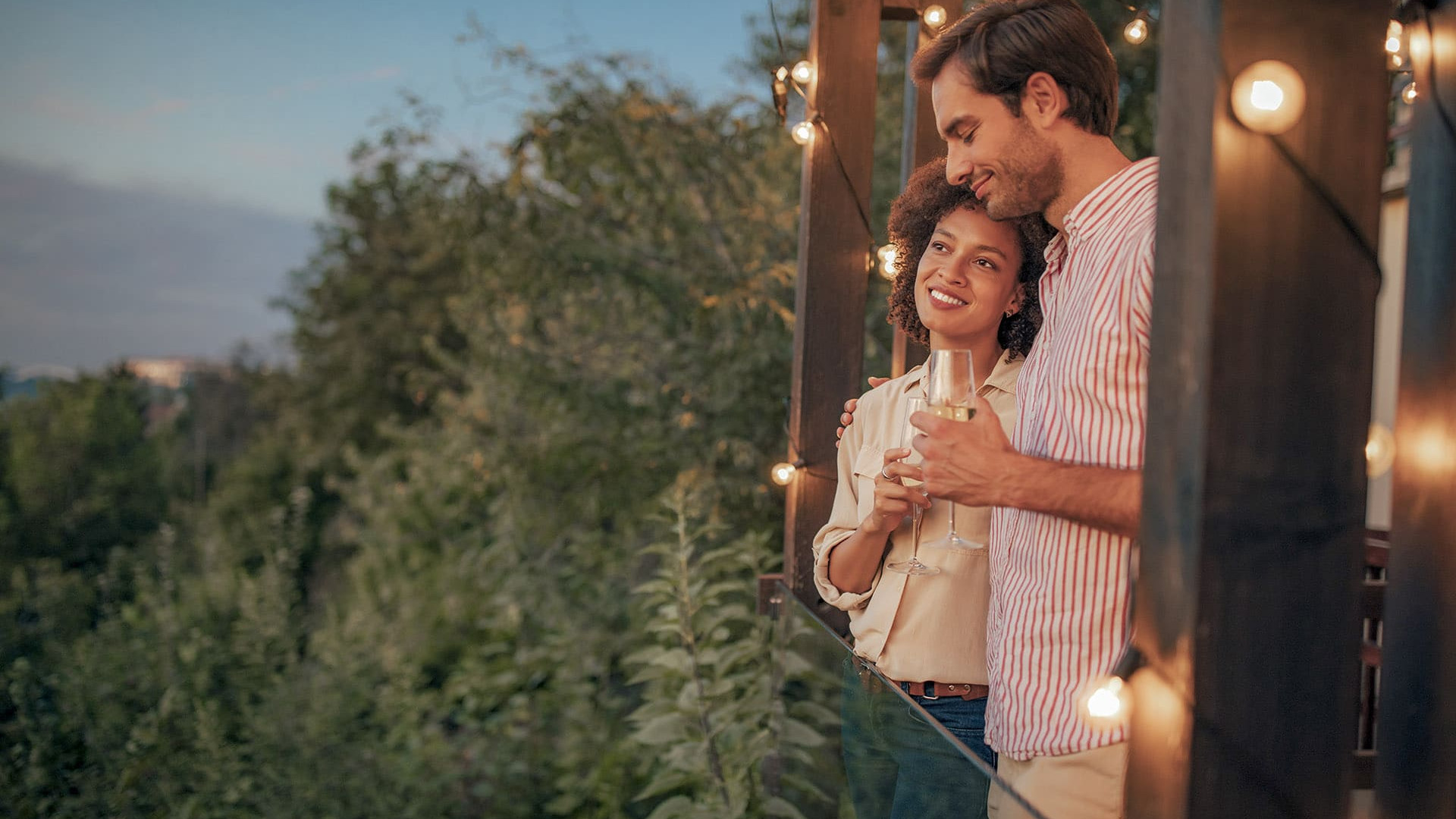 Couple qui prend l'apéro au coucher du soleil en partageant un verre de vin sur la terrasse, un instant de pur romantisme.