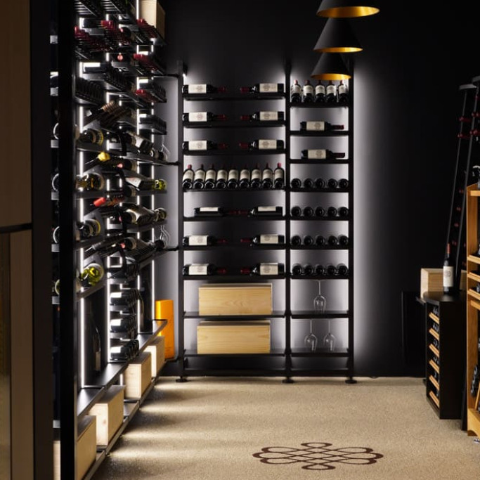 Belle mise en scène des vins avec ce rangement design en métal noir et ses étagères aériennes avec supports bouteille individuels.