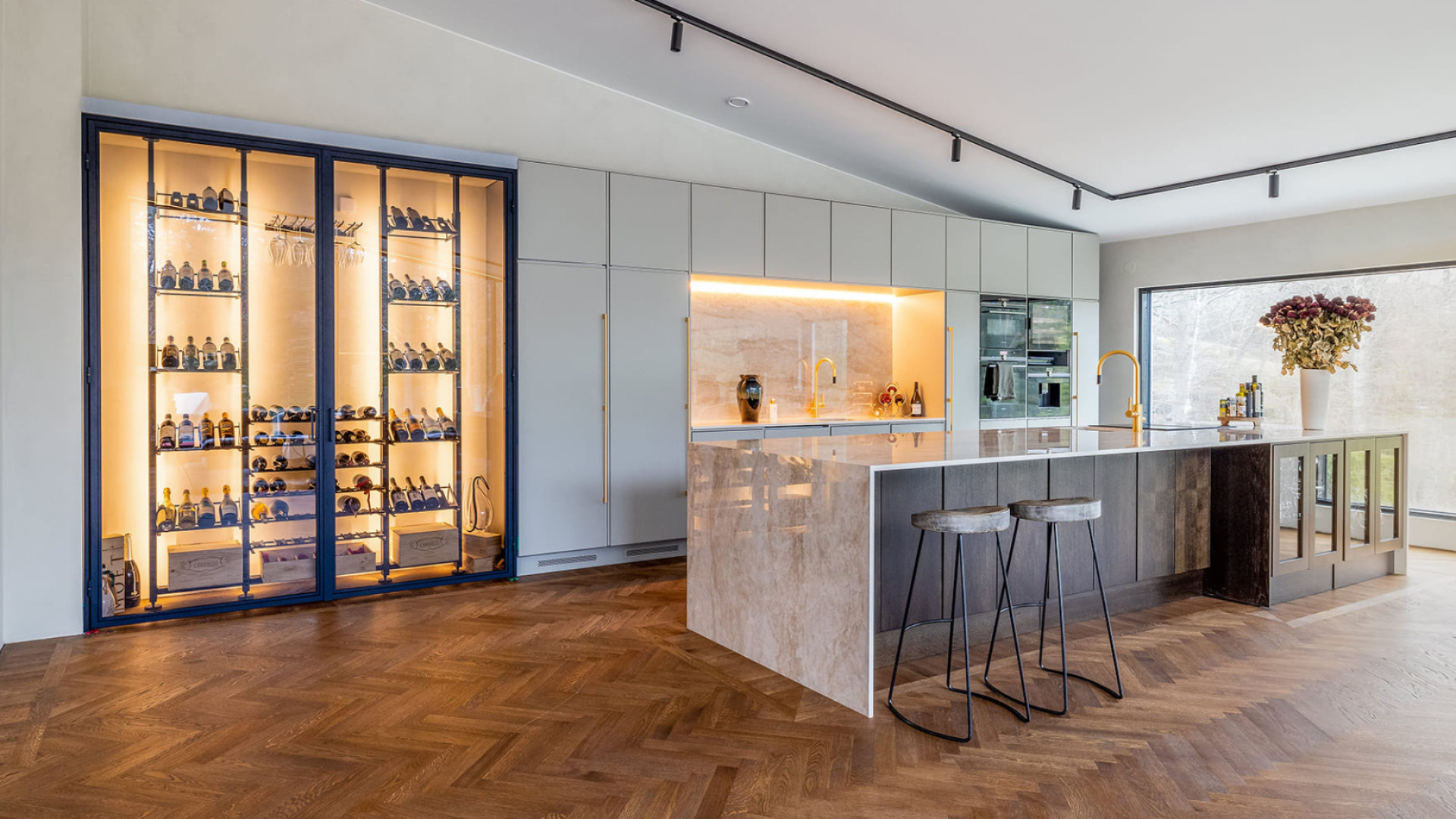 Caves à vin de rêve - Exemple de création d'une vitrine à vin encastrée dans le mur d'un intérieur contemporain et luxueux avec un ilot de cuisine en marbre.