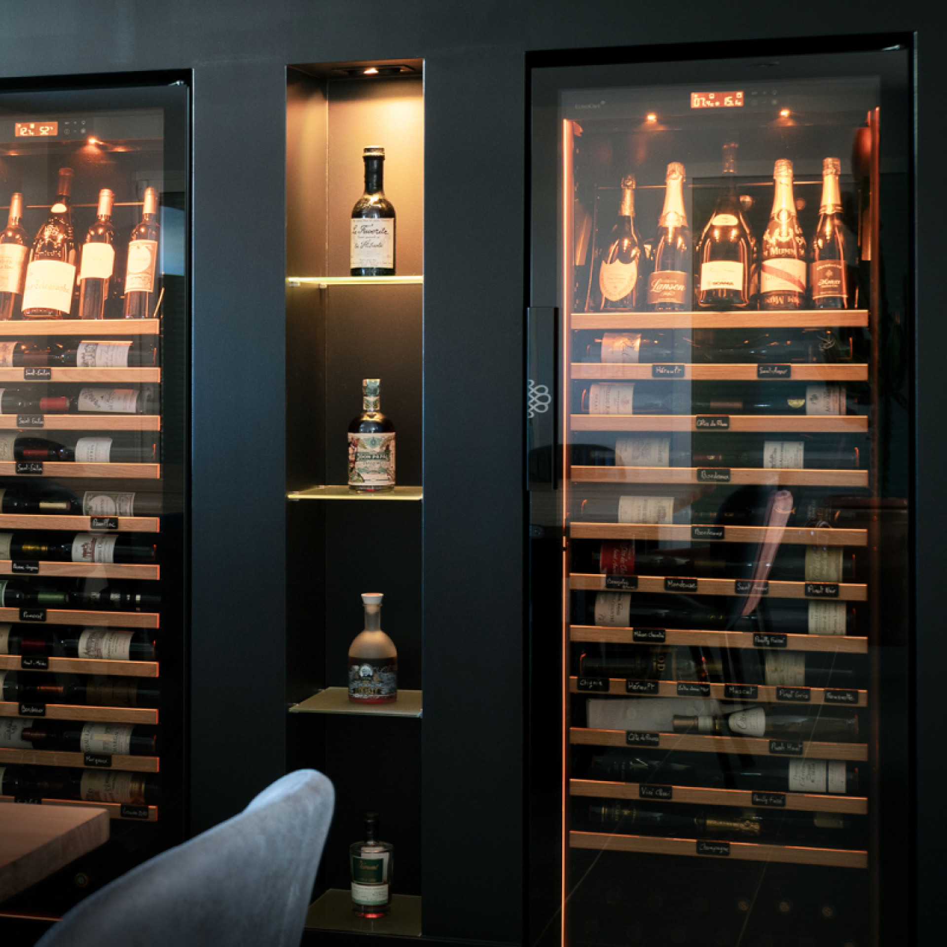 Caves à vin professionnelles avec options premium, encastrées dans une niche dans le mur, avec une belle mise en lumière de bouteilles dans l'armoire.