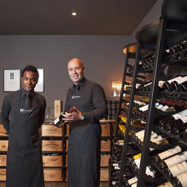 Salle de dégustation avec sommelier conseillant un client. Aménagement cave à vin professionnelle. Rayonnages vin caviste, restaurant. Salle de dégustation avec sommelier conseillant un client. Aménagement cave à vin professionnelle. Rayonnages vin caviste, restaurant.